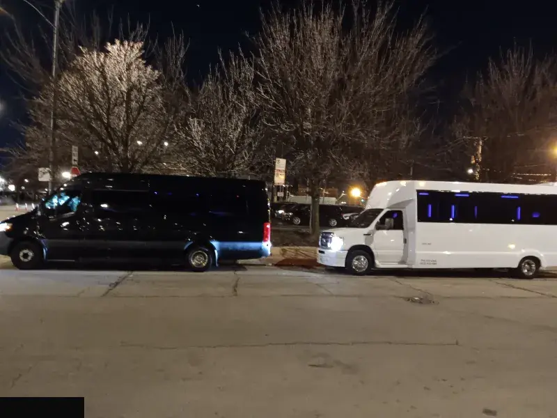 Two Royal Carriage party buses parked at night in Chicago, one black and one white